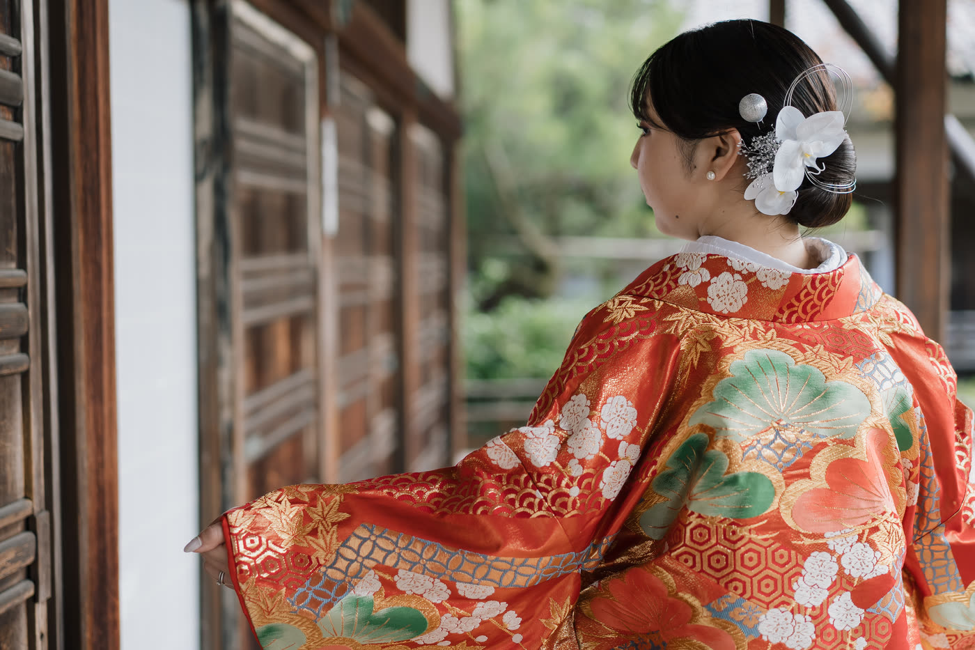 Bride in a red iro-uchikake kimono in a Kyoto temple corridor, illustrating a guide to choosing wedding kimono