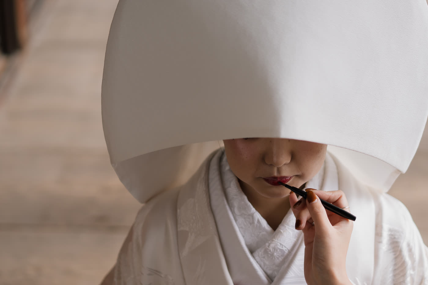 Bride in a white wataboshi hood having her make-up checked before a pre-wedding shoot in Kyoto