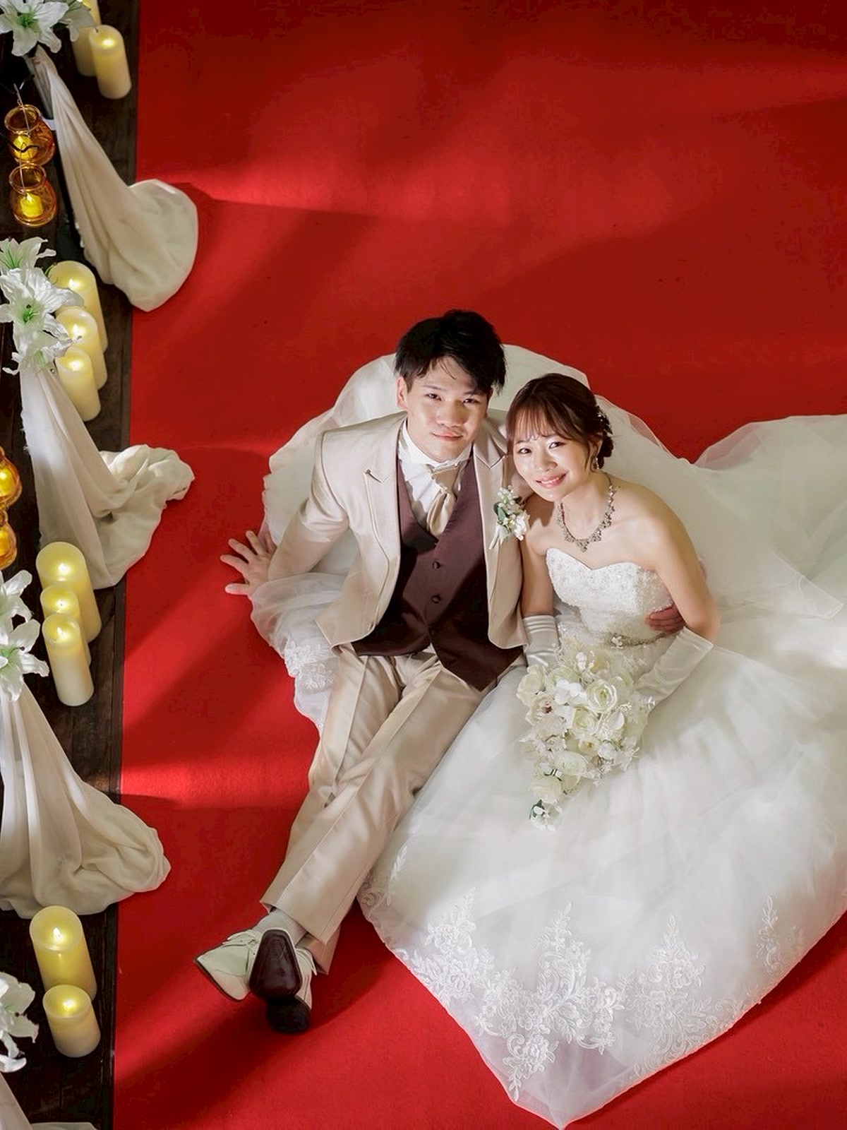Couple photographed from above on a red ceremonial cloth at their wedding reception