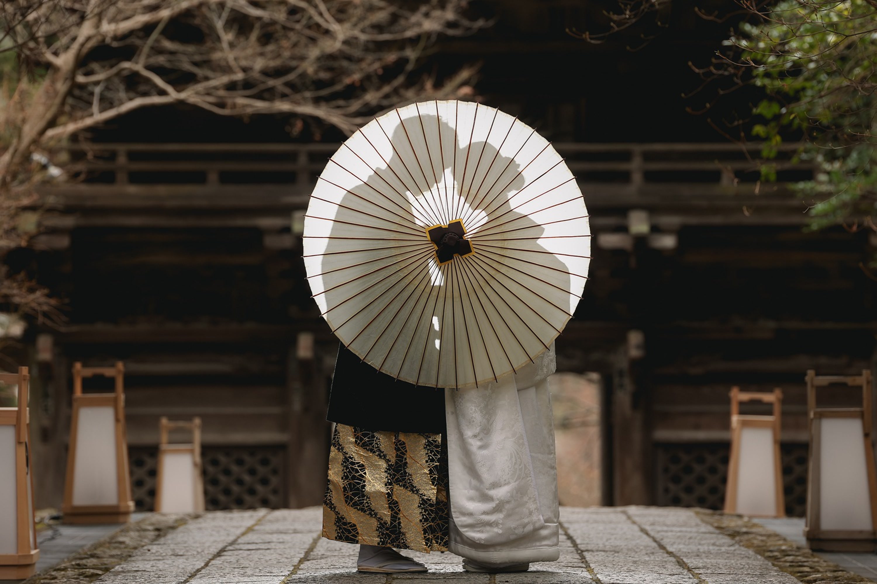 Silhouette of a couple behind a paper umbrella at a shrine gate in Japan, on a pre-wedding photoshoot
