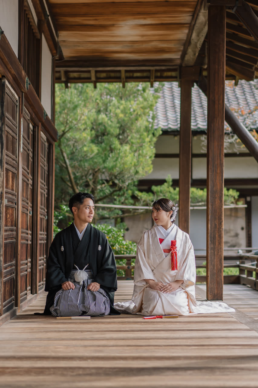 Bride and groom seated on the veranda of a Kyoto temple with the garden behind them