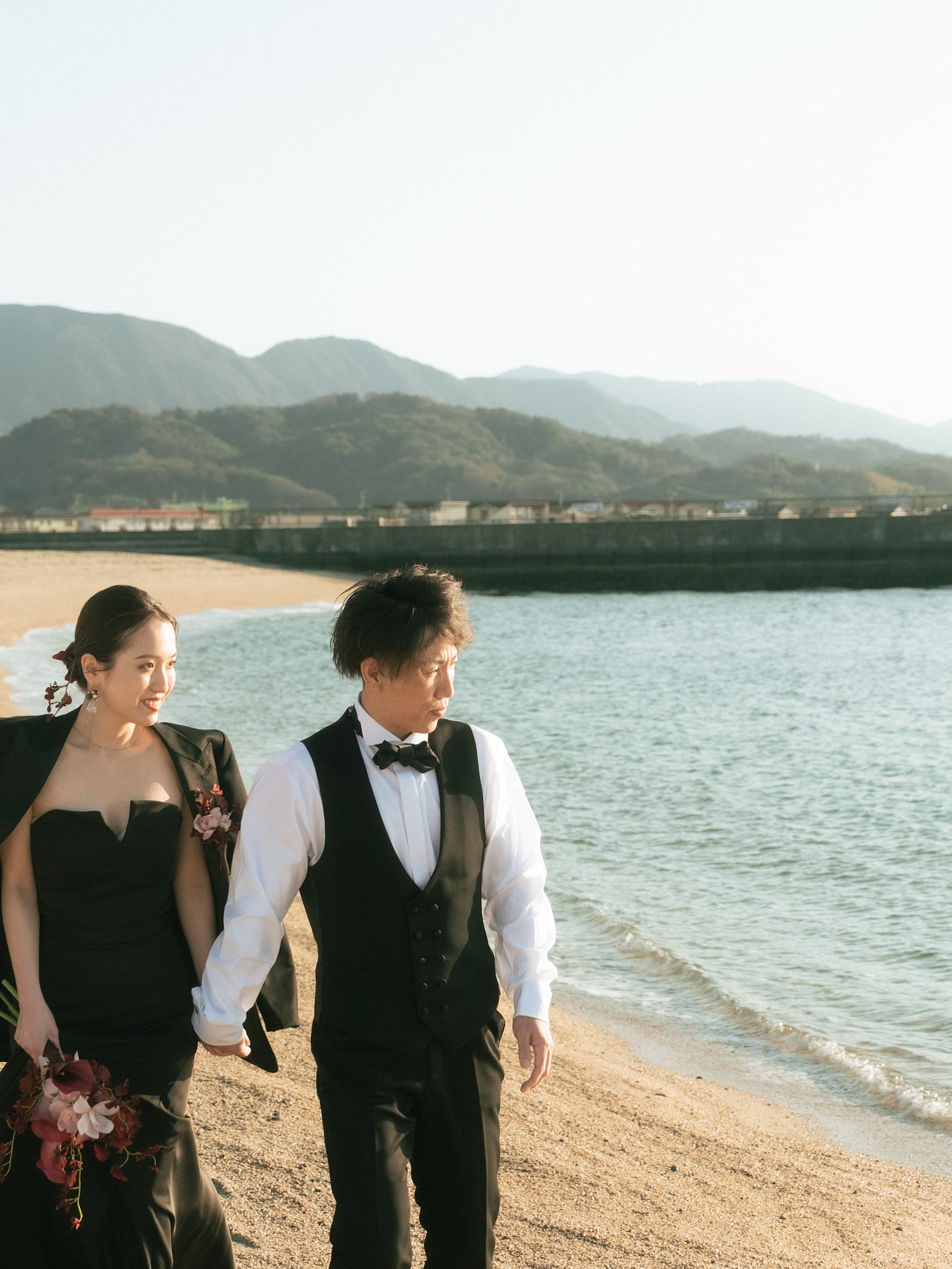 Couple walking barefoot along the shoreline in Okinawa in formal wear