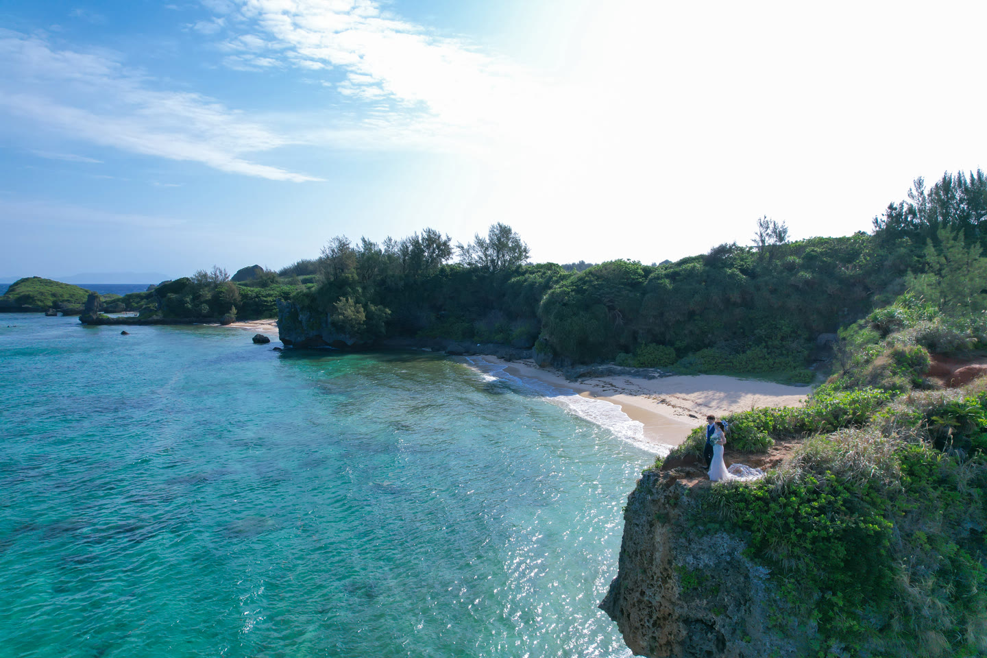 Couple standing above a rocky Okinawa cove