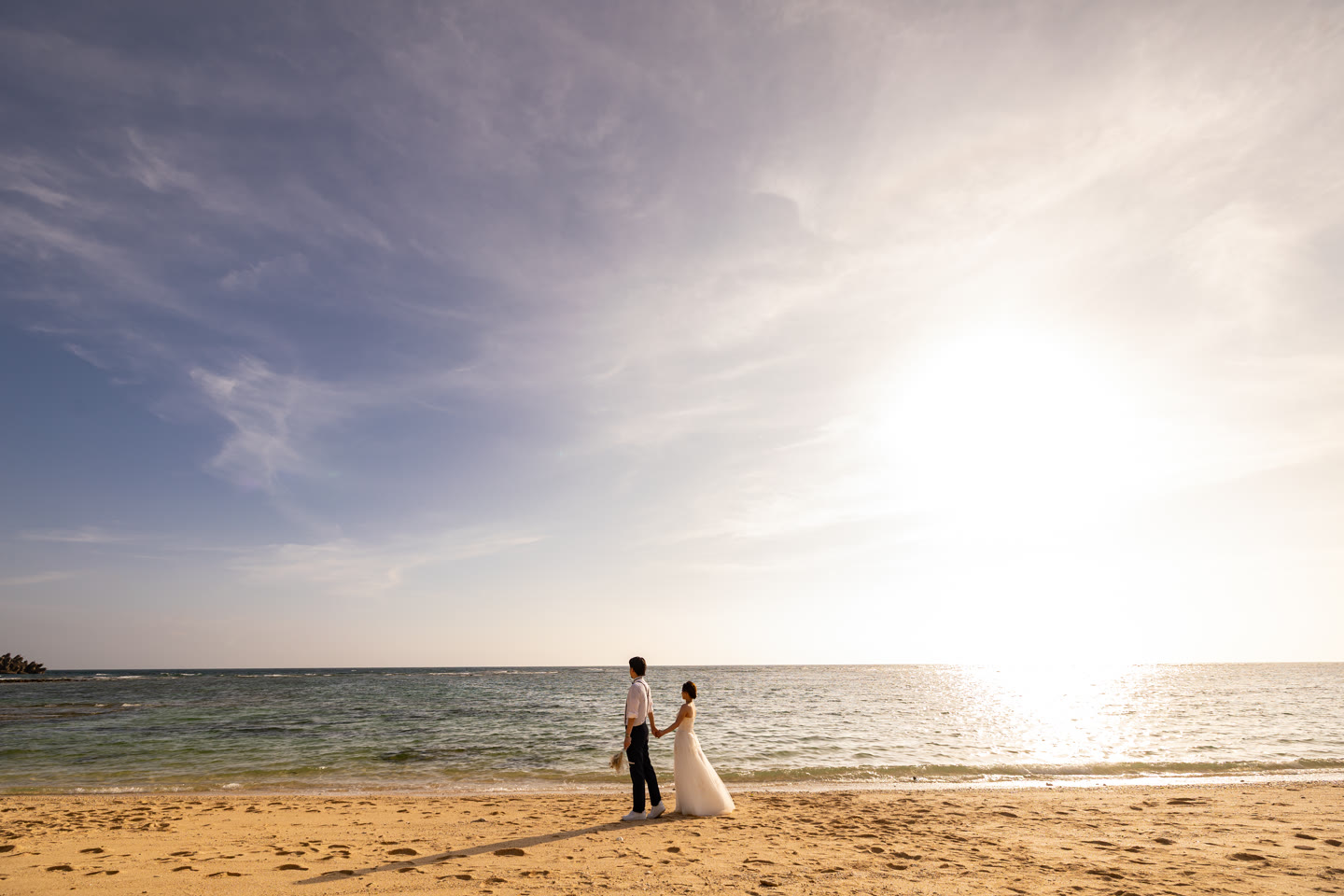 Couple on an Okinawa shoreline as the sun meets the sea