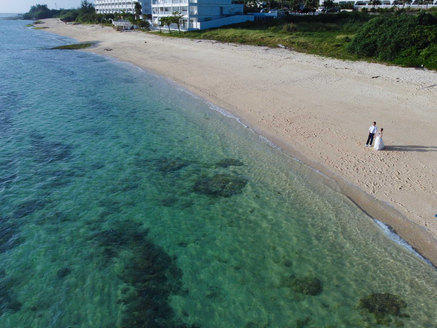 Couple on white sand beside turquoise Okinawa water