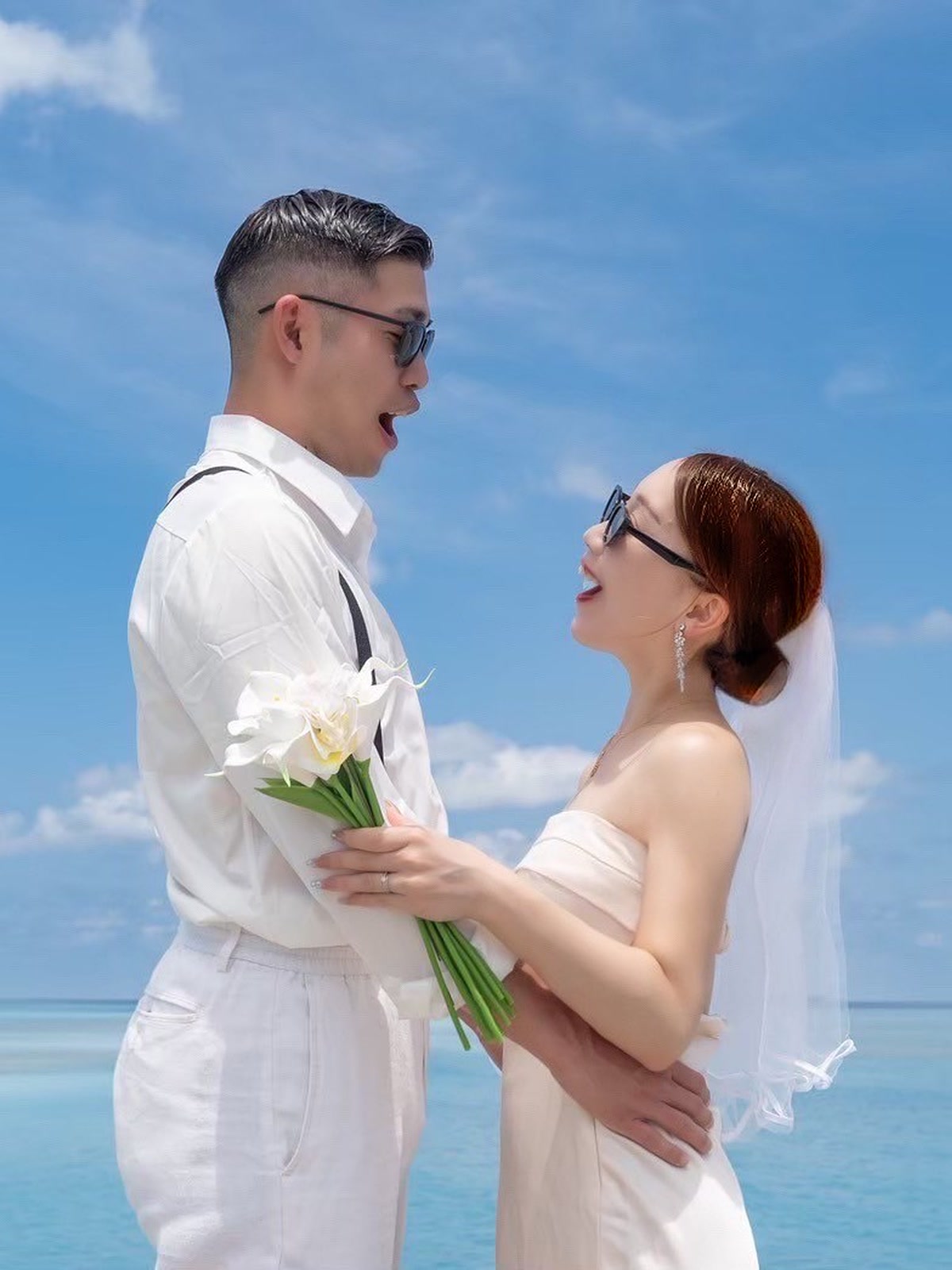 Couple in wedding dress and white suit by the turquoise sea in Okinawa